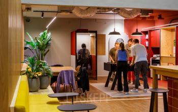 Gezellige kantoorruimte huren in Amsterdam Oost aan Science Park 301, met een speelse sfeer waar mensen ontspannen een potje tafelvoetbal spelen. Moderne inrichting met veel groen en kleurrijke accenten.