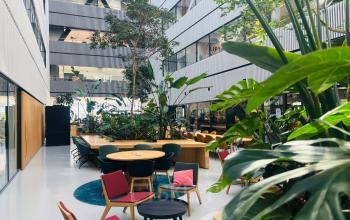 Ruim atrium met veel groen en kleurrijk meubilair in kantoorpand op Science Park 301, Amsterdam Oost. Ideaal voor kantoorruimte huren met een open en uitnodigende sfeer.