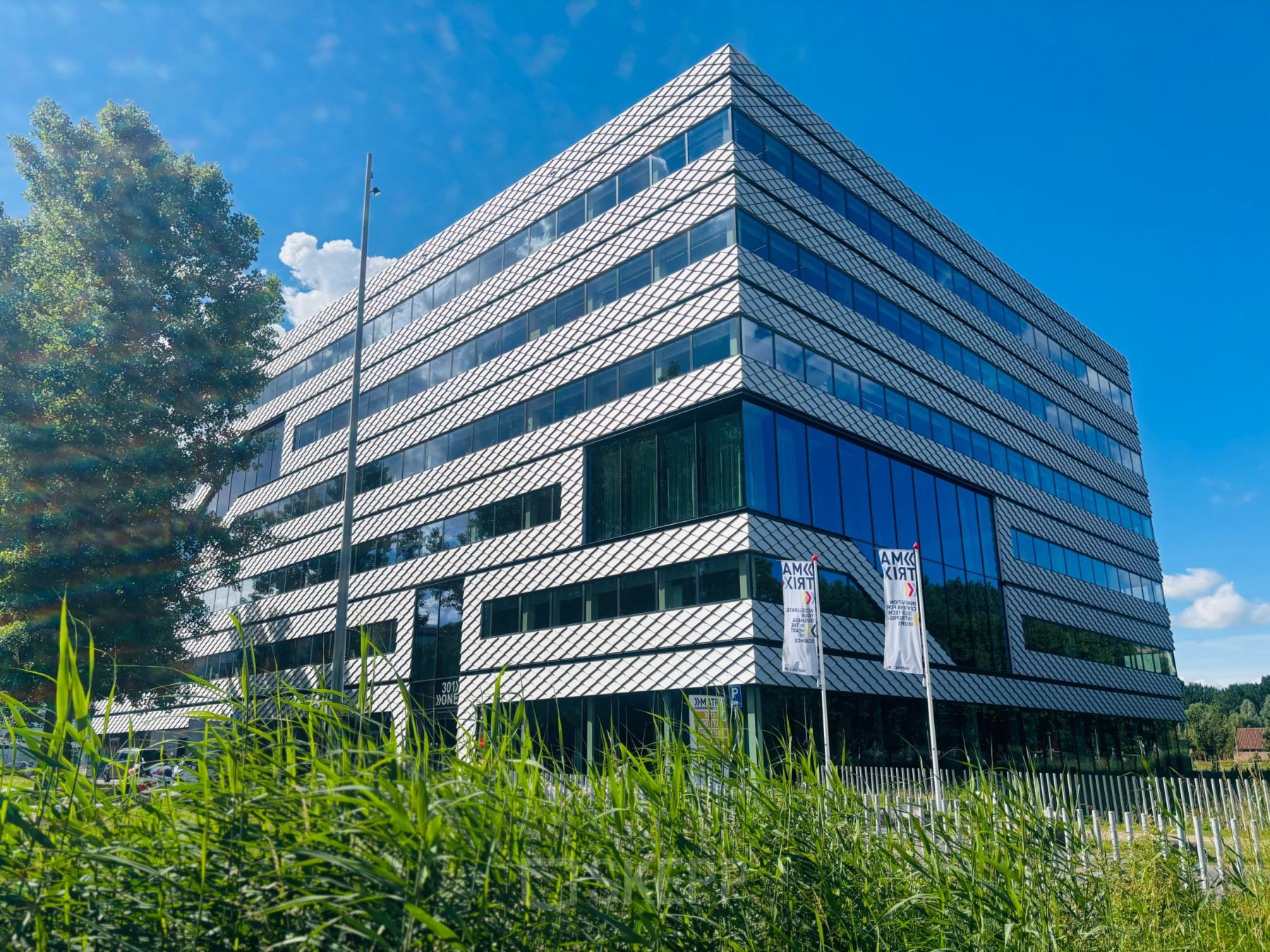 Modern kantoorpand op Science Park 301 in Amsterdam Oost met glas en staal, geschikt voor kantoorruimte huren. Omgeven door groen en een heldere lucht.