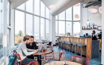 Helder kantoorpand in Amsterdam Oost met grote ramen, moderne inrichting en twee mensen aan het werk op Weesperstraat 61.