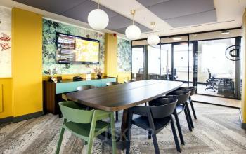 Grote vergaderruimte in een kantoorpand aan de Weesperstraat 61, Amsterdam Oost, ingericht met moderne meubelen en een grote tafel, met een glazen wand aan de rechterkant.