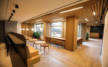 Modern ingerichte werkruimte met houten accenten en zitgedeelten op Apollolaan 151 in Amsterdam Oud Zuid. Ideaal voor kantoorruimte huren met natuurlijke lichtinval en stijlvolle inrichting.