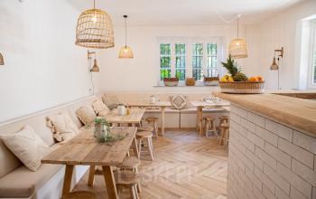 Sfeervolle en lichte kantoorruimte in een kantoorpand aan Emmalaan 7-9, Amsterdam Oud Zuid, met houten tafels, kussens en hanglampen. Ideaal voor huren als creatieve werkplek.