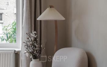 Stijlvolle hoek van een kantoor aan de Emmalaan 7-9 in Amsterdam Oud Zuid, met een comfortabele stoel, bijzettafel en een lamp naast een groot raam.