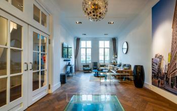 Stijlvolle kantoorruimte huren op PC Hooftstraat 150, Amsterdam Oud Zuid, met houten vloer, moderne inrichting en grote ramen, ideaal voor zakelijke ontmoetingen.