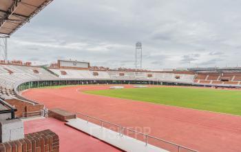 Buitenaanzicht van het Olympisch Stadion in Amsterdam met omringende atletiekbaan, ideaal als locatie voor evenementen of kantoorruimte huren.