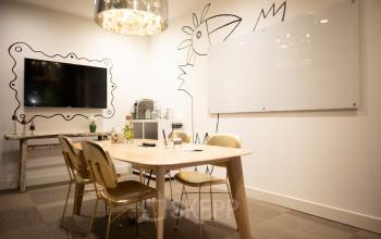 Kantoorruimte huren in het Olympisch Stadion 24-28, Amsterdam Oud-Zuid. Vergaderruimte met muurdecoraties, tafel, stoelen, whiteboard en flatscreen.