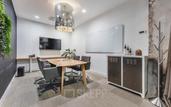 Moderne kantoorruimte huren in Amsterdam Oud Zuid, kantoorpand met vergadertafel, stoelen, televisie en groene wanddecoratie.