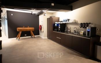 Moderne pantry in kantoorpand op Olympisch Stadion 24-28, Amsterdam Oud Zuid, met koffiezetapparaten en een gym toestel.