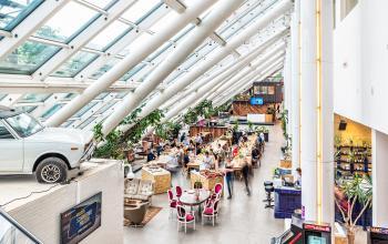Ruime en lichte kantoor met glazen dak op Johan Huizingalaan 400, Amsterdam Riekerpolder, vol met mensen die samenwerken aan tafels.