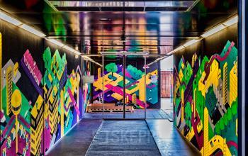 Ingang van het kantoorpand op Johan Huizingalaan 400, Amsterdam Riekerpolder, met kleurrijke muurschilderingen. Ideale plek voor bedrijven die kantoorruimte zoeken in een inspirerende omgeving.