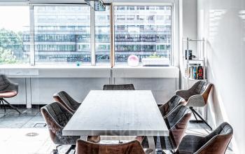 Kantoorruimte huren aan de Johan Huizingalaan 400, Amsterdam Riekerpolder. Moderne werkruimte met grote ramen, industrieel plafond en een grote tafel met zes stoelen. Veel daglicht, ideaal voor vergaderingen.