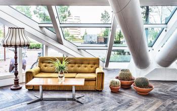 Moderne kantoorruimte met grote ramen op Johan Huizingalaan 400 in Amsterdam Riekerpolder, met comfortabele zitplaatsen en planten. Ideaal voor wie een creatieve werkruimte wil huren.