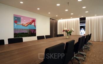 Moderne vergaderruimte in kantoorpand op Johan Huizingalaan 400, Amsterdam Riekerpolder met lange houten tafel, comfortabele stoelen en creatieve kunst aan de muur. Ideaal voor het huren van een inspirerende werkplek.