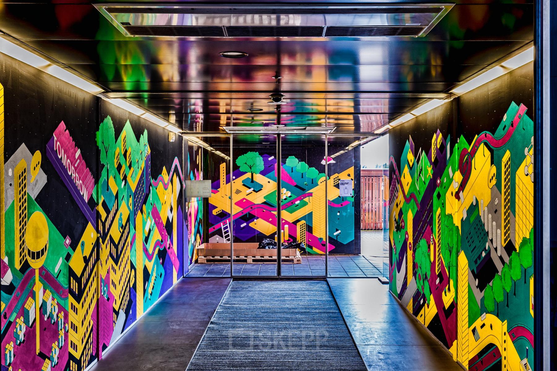 Ingang van het kantoorpand op Johan Huizingalaan 400, Amsterdam Riekerpolder, met kleurrijke muurschilderingen. Ideale plek voor bedrijven die kantoorruimte zoeken in een inspirerende omgeving.