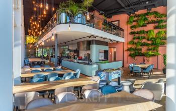 Moderne en ruime kantoorruimte op John M. Keynesplein 4-10 in Amsterdam Riekerpolder met gemeubileerd interieur, plantenwand en speelse verlichting, ideaal om een kantoor te huren voor zakelijke activiteiten.