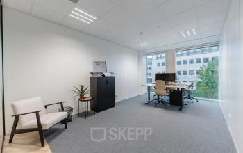 Een lichte kantoorruimte met een raam met uitzicht, voorzien van bureau, stoelen en opbergruimte. Ideaal voor kantoorruimte huren op John M. Keynesplein in Amsterdam Riekerpolder.