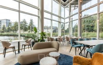 Lichte en moderne kantoorlounge met hoge ramen en comfortabel meubilair bij kantoorpand op John M. Keynesplein, Amsterdam Riekerpolder.