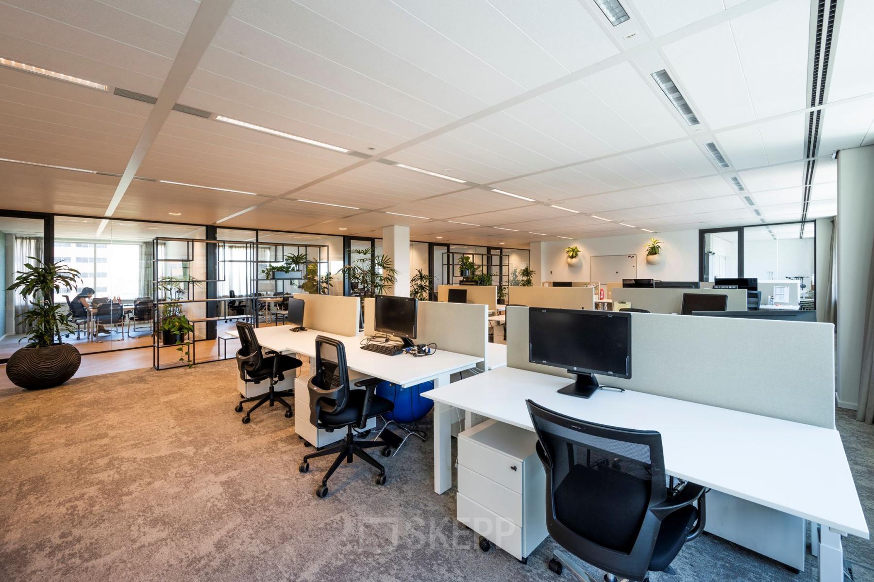 Moderne kantoorruimte huren op Thomas R. Malthusstraat 1-3, Amsterdam Riekerpolder met open werkplekken, bureaus, stoelen en enkele aanwezige medewerkers bezig met zakelijke activiteiten.