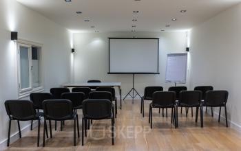 Vergaderruimte in kantoorpand Poortland 66, Amsterdam Sloterdijk met projectiescherm en stoelen.