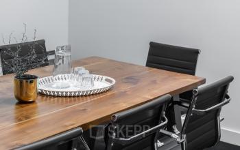Vergadertafel met zwarte stoelen, glazen karaf en glazen op een dienblad in kantoorpand Poortland 66, Amsterdam Sloterdijk, geschikt voor kantoorruimte huren.