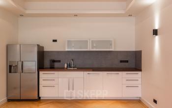 Strakke pantry in het kantoorpand Poortland 66, Amsterdam Sloterdijk, met moderne koelkast en lichte houten vloer. Ideaal voor kantoorruimte huren met focus op functionaliteit en stijl.