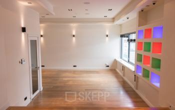 Lege kantoorruimte te huur op Poortland 66, Amsterdam Sloterdijk. Ruime en lichte kamer met houten vloer en kleurrijke wanddecoratie.