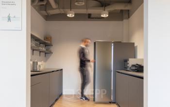 Kantine van het kantoorpand aan de Teleportboulevard 120 in Amsterdam Sloterdijk, met een persoon die een koelkast opent.