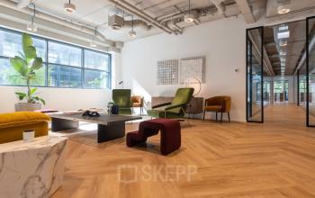 Kantoorruimte huren in Amsterdam Sloterdijk, met een moderne lounge, houten vloeren, stijlvolle meubels en ruime ramen voor veel natuurlijk licht. Inspirerende plek voor werk en ontspanning.