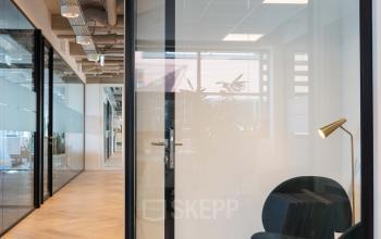 Ingang van een modern kantoorpand aan Teleportboulevard 120 in Amsterdam Sloterdijk, met glazen deuren en stijlvolle zitjes die geschikt zijn voor kantoorruimte huren.