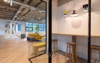 Modern kantoorpand op Teleportboulevard 120, Amsterdam Sloterdijk, geschikt voor kantoorruimte huren, met fraaie glazen scheidingswanden en kleurrijke meubels.