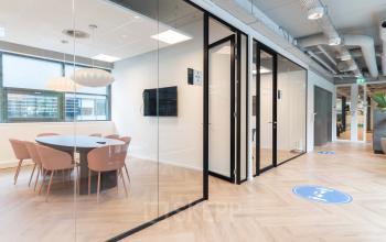 Moderne kantoorruimte met glazen wanden en een vergadertafel op Teleportboulevard 120 in Amsterdam Sloterdijk.