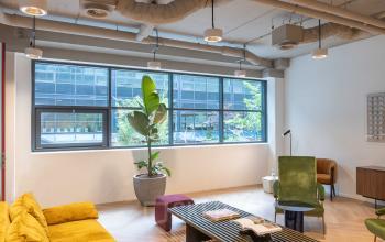 Stijlvolle kantoorruimte huren in Amsterdam Sloterdijk, gelegen aan Teleportboulevard 120. De ruimte is ingericht met kleurrijke meubels en planten, ideaal voor creatieve brainstormsessies en informele vergaderingen.