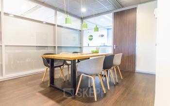Vergaderruimte in kantoor op Radarweg 29, Amsterdam Sloterdijk, met moderne glazen wanden, houten tafel en stoelen. Geschikt voor zakelijke bijeenkomsten, ideaal voor kantoorruimte huren.