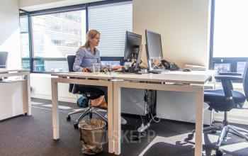 Moderne kantoorruimte huren aan de Radarweg 29, Amsterdam Sloterdijk. Een persoon werkt aan een bureau met computers en bureaustoelen. Grote ramen zorgen voor veel natuurlijk licht.