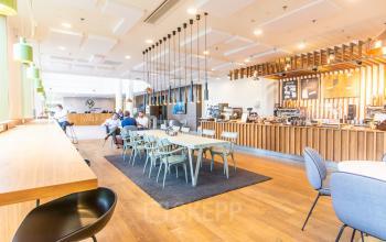 Kantoorruimte huren aan de Radarweg 29 in Amsterdam Sloterdijk. Gezellige en moderne werkplek met zitgedeeltes en een bar. Mensen voeren zakelijke gesprekken in een informeel café-achtige sfeer.