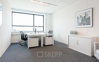 Goed verlichte kantoorruimte huren aan Teleportboulevard 110 in Amsterdam Sloterdijk met strak interieur, twee bureaus en een grote raam. Ideaal voor een productieve werksfeer in een kantoorpand.