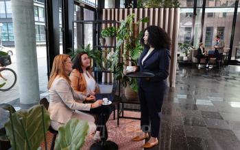 Moderne kantoorruimte op Teleportboulevard 110, Amsterdam Sloterdijk, met mensen in een zakelijke omgeving. Gezellig gemeubileerd met planten en zitgelegenheid.