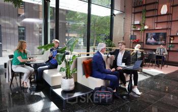 Moderne kantoorruimte aan de Teleportboulevard 110 in Amsterdam Sloterdijk met mensen die vergaderen en koffie drinken tussen planten en stijlvol meubilair.