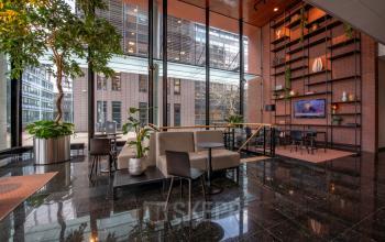 Stijlvolle kantoorruimte huren aan Teleportboulevard 110 in Amsterdam Sloterdijk, met moderne inrichting, grote ramen, planten en zithoeken, geschikt voor diverse zakelijke activiteiten.