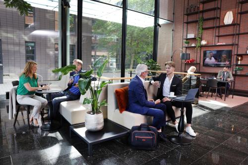 Zakelijke professionals in een modern ingerichte lounge van een kantoorpand aan Teleportboulevard 110, Amsterdam Sloterdijk, waar men comfortabel kan huren.