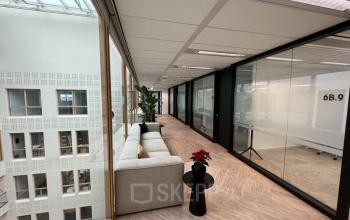 Interieur van kantoorruimte op Kabelweg 57 in Amsterdam Sloterdijk met een lichte zithoek en veel glas. Ideaal om een kantoor te huren vanwege de moderne uitstraling.