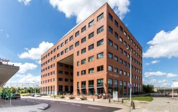 Buitenkant van kantoorpand op Kabelweg 57 in Amsterdam Sloterdijk, met heldere blauwe lucht en moderne architectuur, ideaal voor kantoorruimte huren.