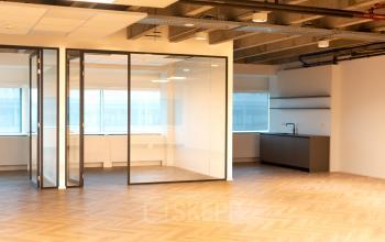 Lege kantoorruimte in Kabelweg 37, Amsterdam Sloterdijk, met glazen wanden, een keukenblok, en een groot raam. Ideaal voor bedrijven die kantoorruimte willen huren in een moderne omgeving.