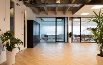 Moderne kantoorruimte op Kabelweg 37, Amsterdam Sloterdijk, met glazen wanden en houten vloer, biedt een uitnodigende sfeer voor zakelijke activiteiten.