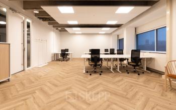 Ruime kantoorruimte met houten vloer en moderne meubels op Kabelweg 37, Amsterdam Sloterdijk. Ideaal voor bedrijven die een kantoor willen huren. Heldere verlichting en grote ramen voor een productieve werkomgeving.