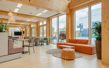 Lichte en moderne kantoorruimte aan de Basisweg 32 in Amsterdam Sloterdijk, met houten elementen en diverse zitplekken. Ideaal voor bedrijven die kantoorruimte huren met een open en uitnodigende sfeer.