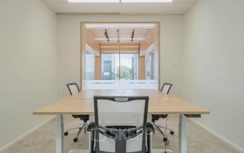 Kantoorpand aan de Basisweg 32 in Amsterdam Sloterdijk met moderne inrichting, lichte muren en houten accent. Geschikt voor kantoorruimte huren met meerdere werkplekken, helder en functioneel design.