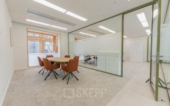 Het interieur van een vergaderruimte in een kantoorpand aan Basisweg 32, Amsterdam Sloterdijk, met glazen wanden en een ronde tafel met vijf stoelen. Kantoorruimte huren mogelijk.