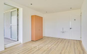 Ongemeubileerde kantoorruimte te huur met een houten vloer, ingebouwde kast en klein wastafel op Tijnmuiden 59 in Amsterdam Sloterdijk.